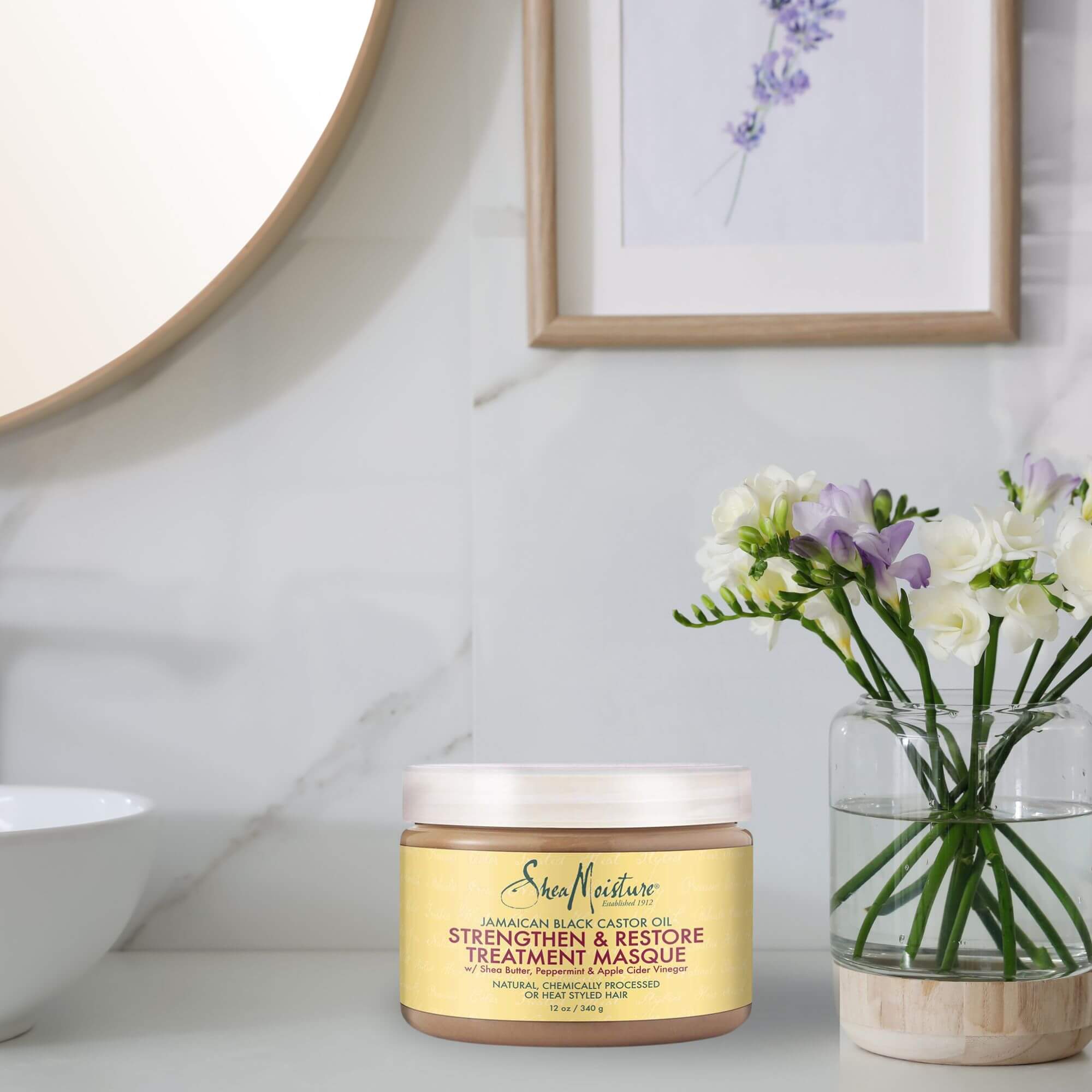 SheaMoisture Jamaican Black Castor Oil Strengthen & Restore Hair Masque, eine Haarmaske, steht auf einem Badezimmerregal. Sie enthält Shea Butter, Pfefferminzöl und Apfelessig zur Stärkung und Revitalisierung von strapaziertem Haar.
